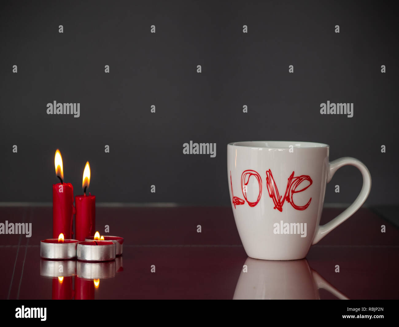 Concetto di amore ancora vita con rosso acceso candele e una colazione cup con la parola amore Foto Stock