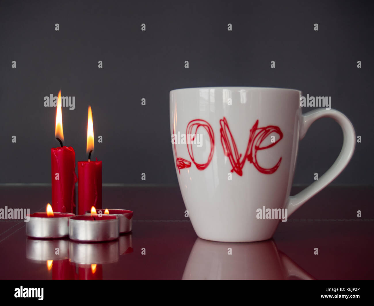 Concetto di amore ancora vita con rosso acceso candele e una colazione cup con la parola amore Foto Stock