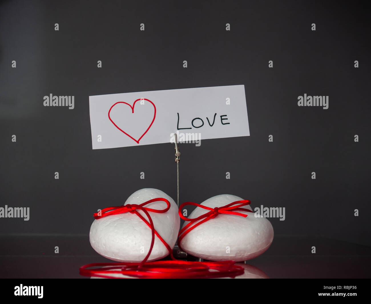 Concetto di amore poliespan due cuori uniti con un filo rosso che  simboleggia la leggenda del filo rosso e una scheda con il testo di amore  Foto stock - Alamy