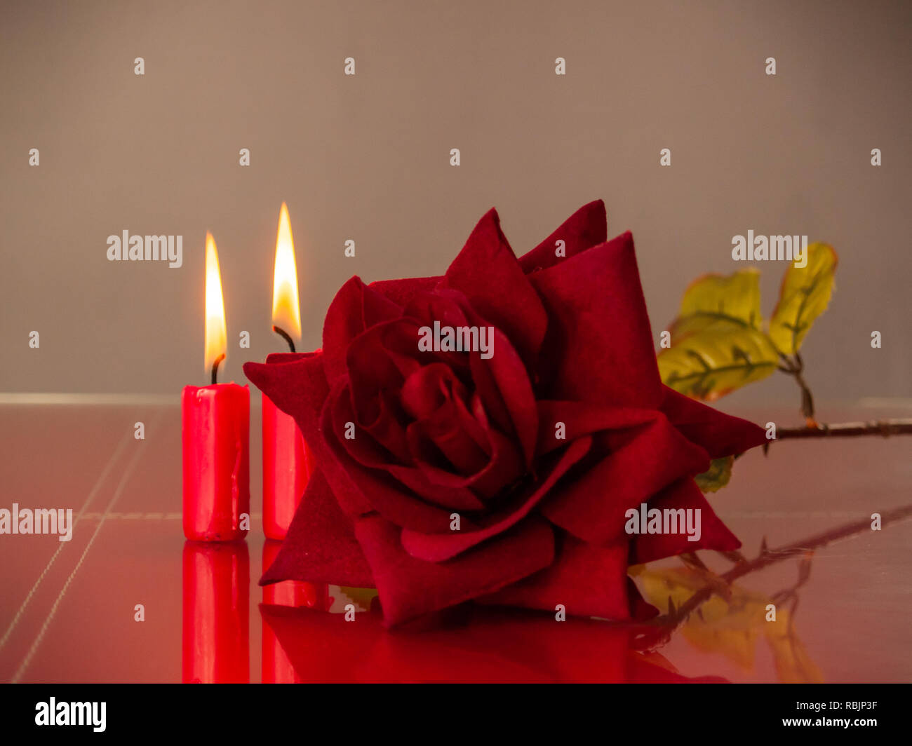 Concetto di amore candele rosse accese e una rosa rossa con un sfondo caldo Foto Stock
