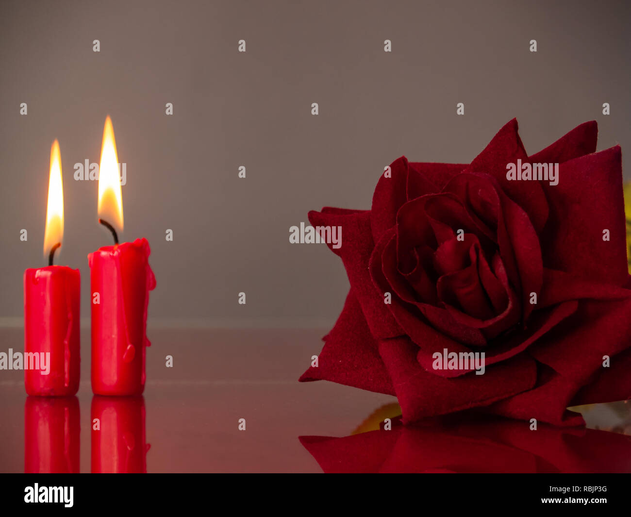 Concetto di amore candele rosse accese e una rosa rossa con un sfondo caldo Foto Stock