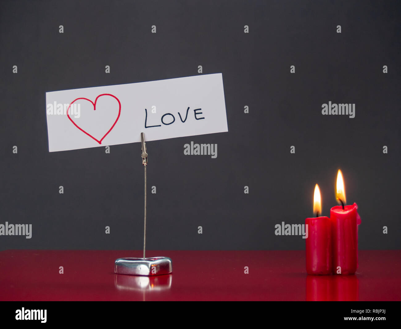 Concetto di amore candele rosse accese e un cuore-supporto sagomato con il testo ti amo Foto Stock