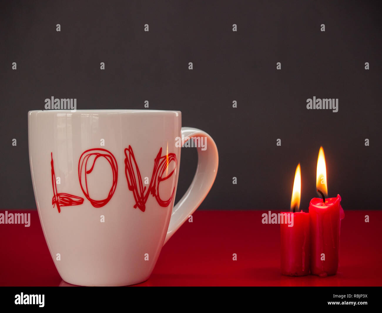 Concetto di amore ancora vita con rosso acceso candele e una colazione cup con la parola amore Foto Stock