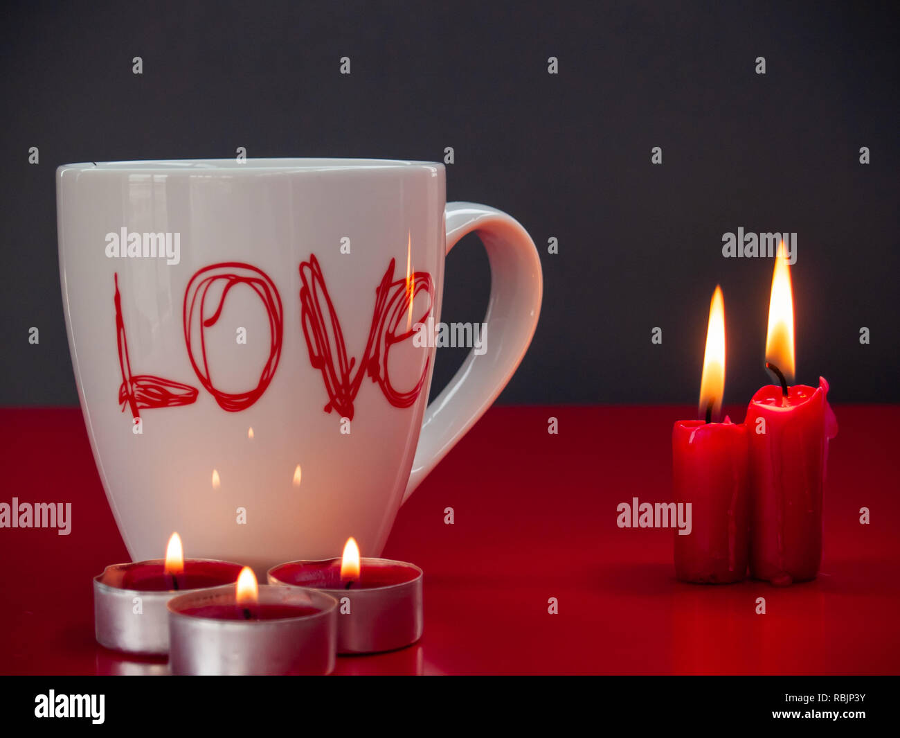 Concetto di amore ancora vita con rosso acceso candele e una colazione cup con la parola amore Foto Stock