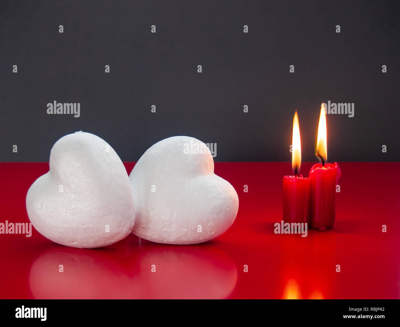 Concetto di amore ancora vita con rosso acceso candele e due cuori poliespan Foto Stock