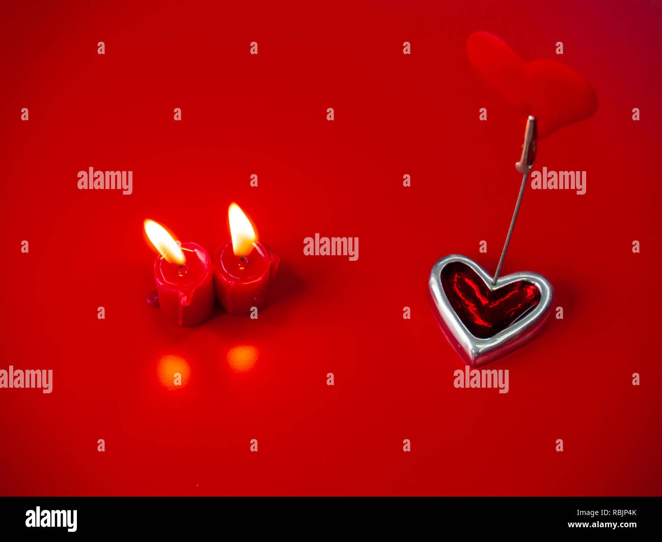 Concetto di amore candele rosse accese e cuore rosso con uno sfondo rosso Foto Stock