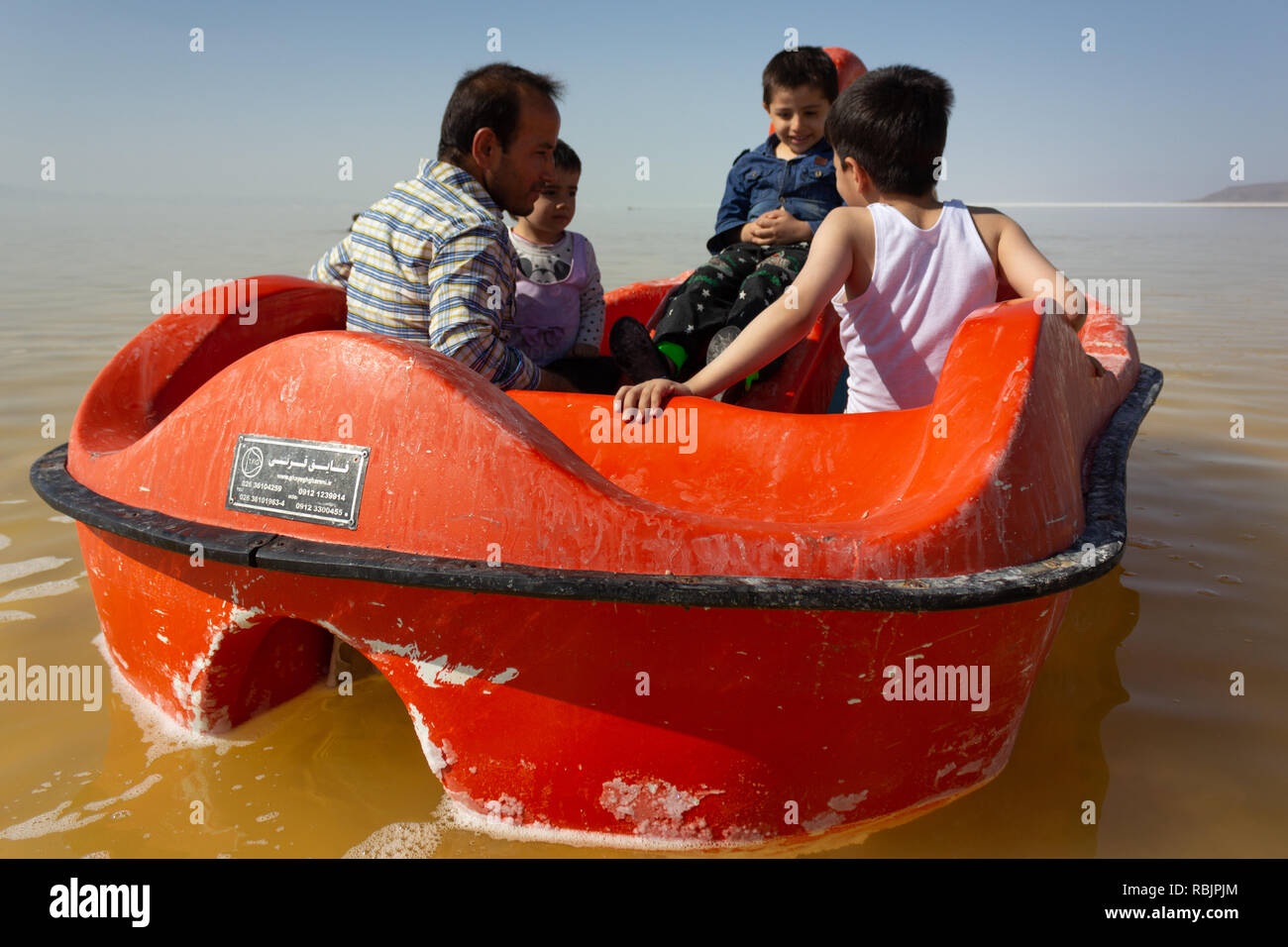 Un uomo è in sella a una barca a pedali con i suoi figli sul lago di Urmia, West Azerbaijan provincia, Iran Foto Stock