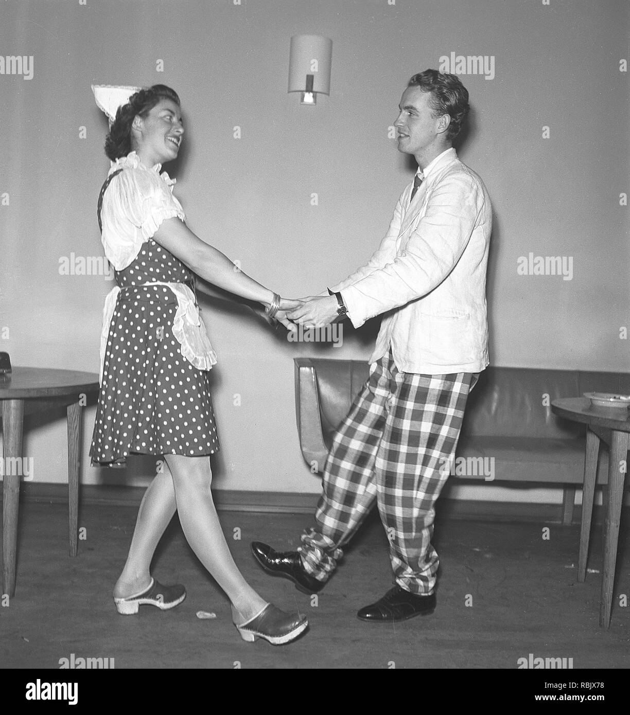 In ballo nel 1940s. Una giovane coppia a teatro danza insieme nei loro costumi di scena. La coppia è stranamente vestito. Egli in pantaloni a scacchi e lei in un abito punteggiato. Foto Kristoffersson Ref M23-3. La Svezia 1945 Foto Stock