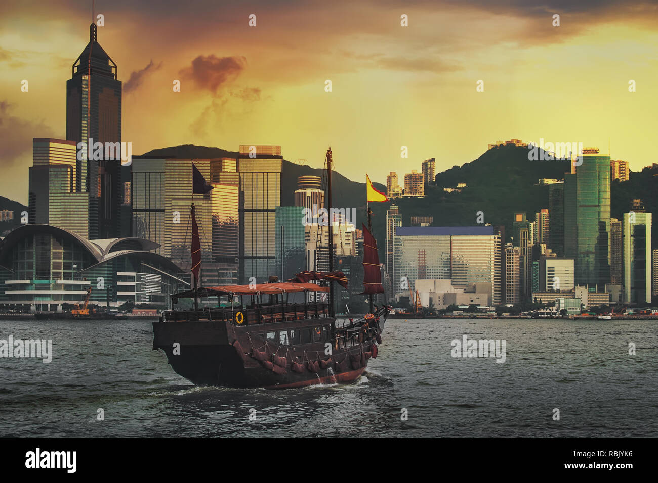 In legno tradizionale barca a vela vela in Porto Victoria al tramonto a Hong Kong, Cina. Foto Stock