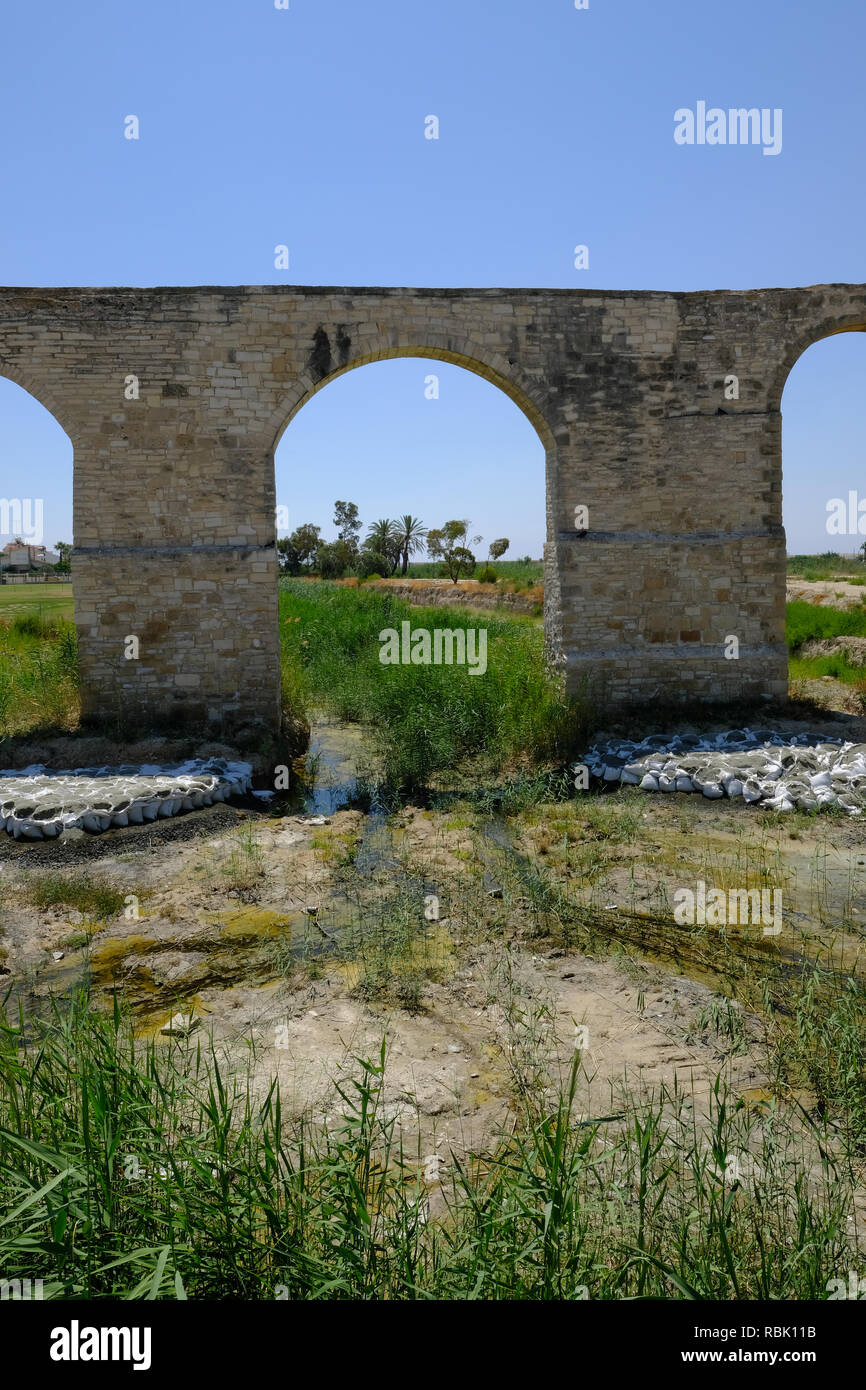 Vista dell acquedotto di Kamares, Larnaca. Colpo verticale guardando attraverso uno degli archi centrali. Alberi di palma che cresce in background. Foto Stock