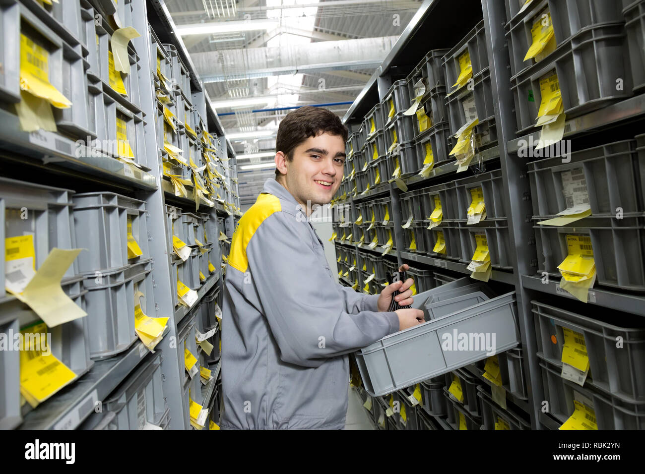 Lavoratore in magazzino tra lunghi scaffali con una varietà di scatole Foto Stock