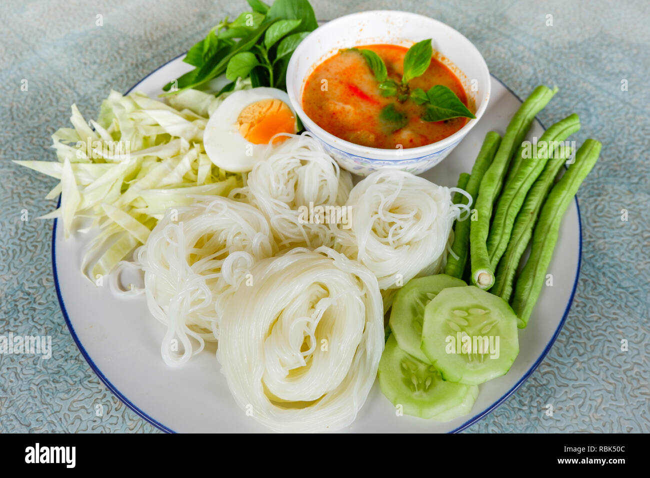 Thai rice noodle or rice vermicelli noodle and curry soup sauce on plate with vegetable yardlong , cucumber  bean and egg / Thai style food delicious Foto Stock
