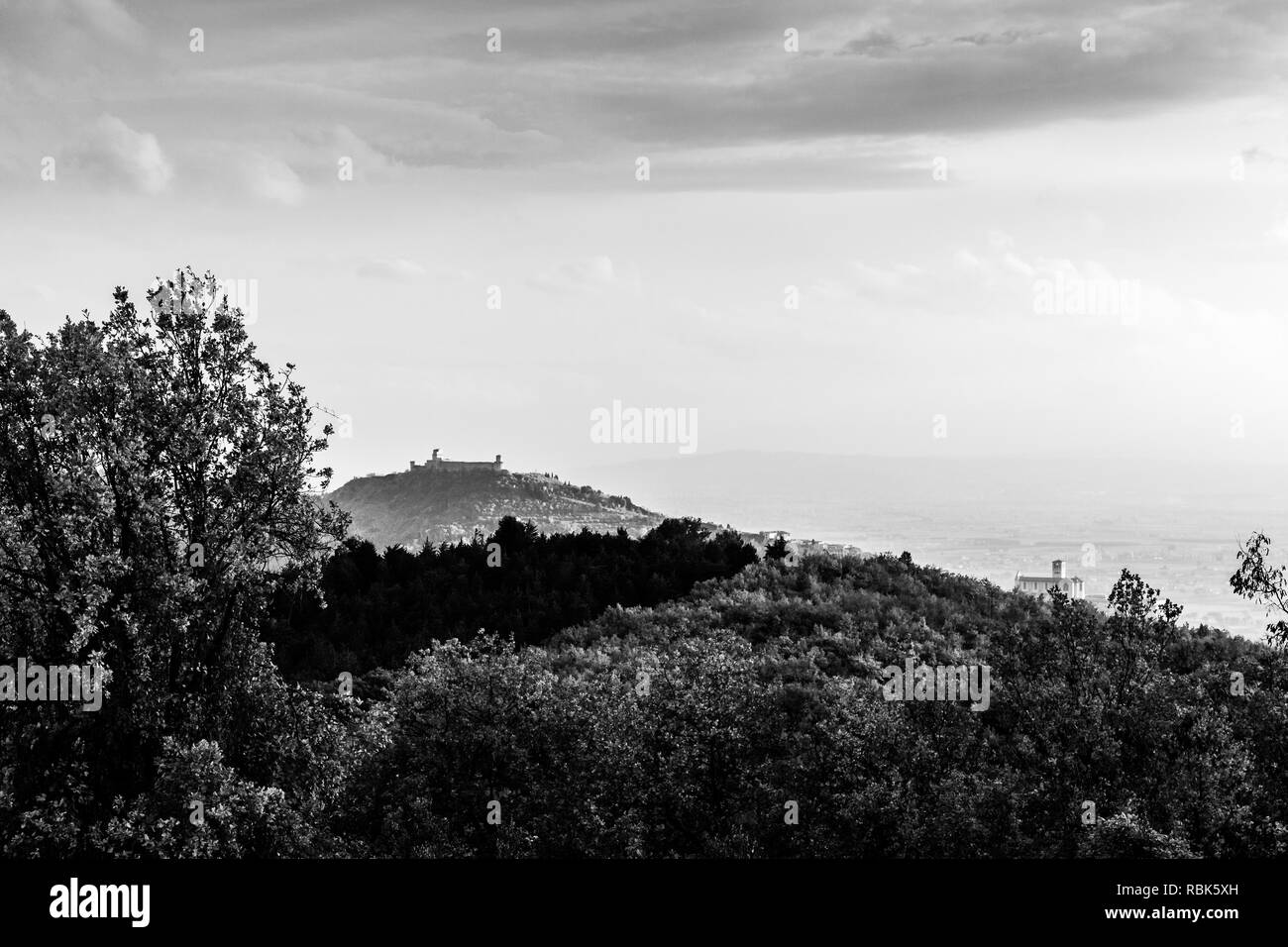 Bellissima vista della città di Assisi (Umbria) in autunno da un luogo insolito, dietro una collina con alberi Foto Stock