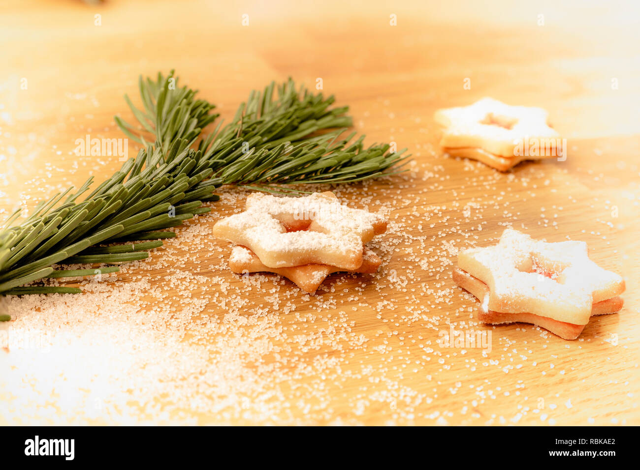 Biscotti di Natale con glassa di zucchero e zucchero semolato sul tavolo di legno accanto al ramo di abete Foto Stock