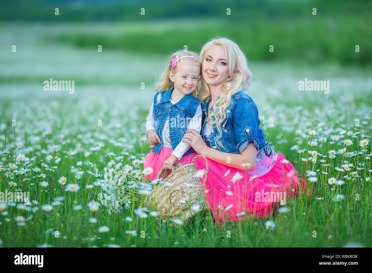 Mamma e figlia su un picnic nella camomilla in campo due belle ragazze  bionde indossano jeans giacca e gonna rosa madre e bambina abbracciando in  ch Foto stock - Alamy
