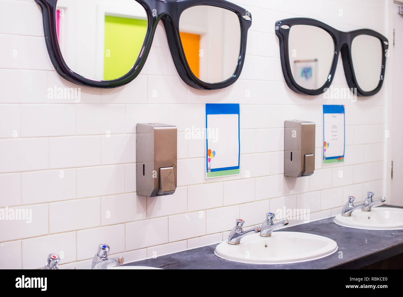 Dissipatore di lavaggio e grandi specchi a forma di occhiali in wc pubblico , fila di inglese due gru lavabo in bagno. Messa a fuoco selettiva, spazio di copia Foto Stock