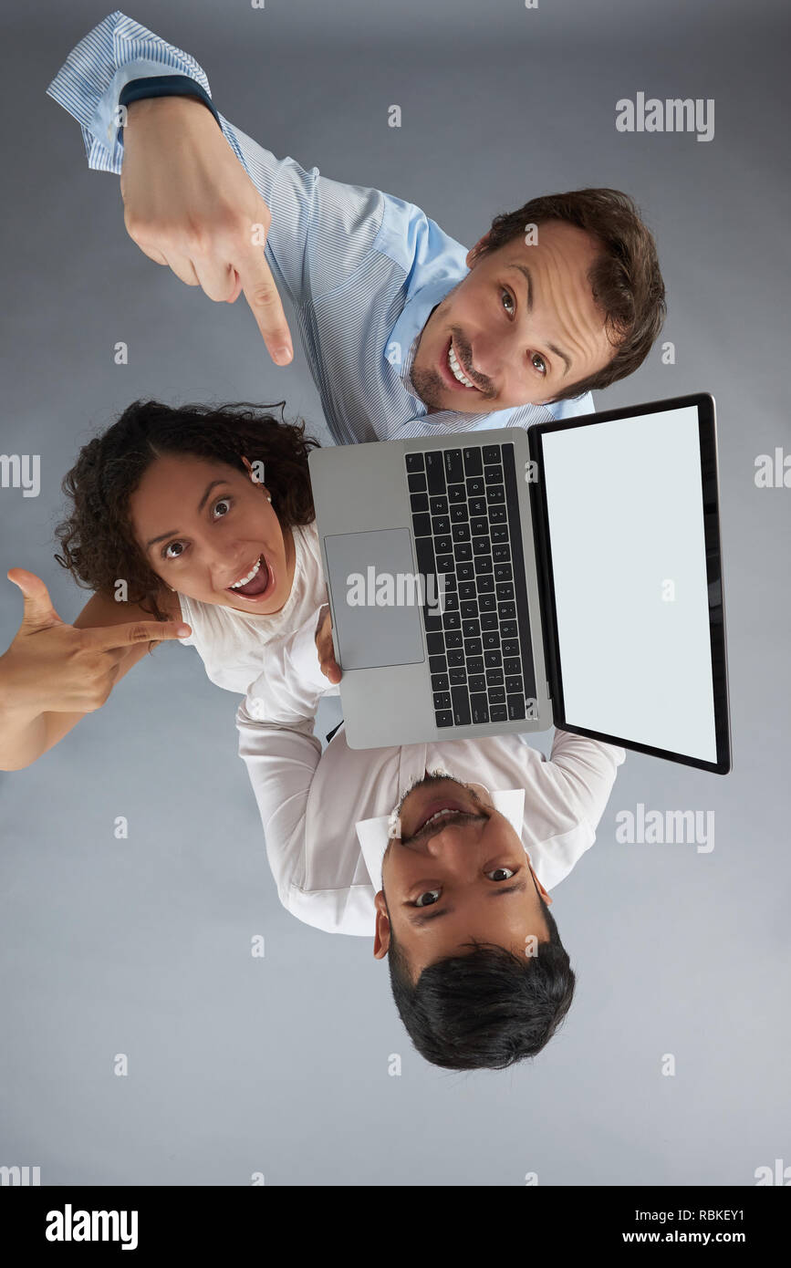 Gruppo di persone tenere il laptop e puntando alla schermata sopra vista dall'alto su grigio di sfondo per studio Foto Stock