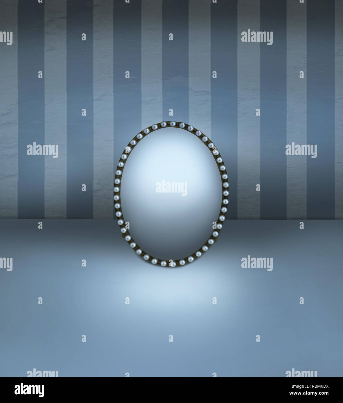 Piccolo specchio con cornice vintage decorata in perle in appoggio su un piano e con la parete a strisce sullo sfondo Foto Stock