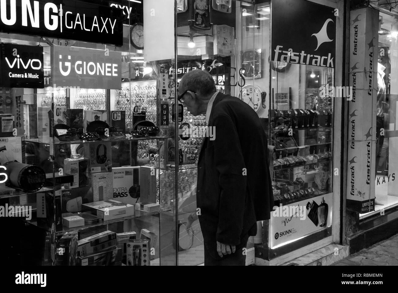 Il vecchio uomo che guarda al negozio di elettronica finestra, Calcutta, West Bengal, India Foto Stock