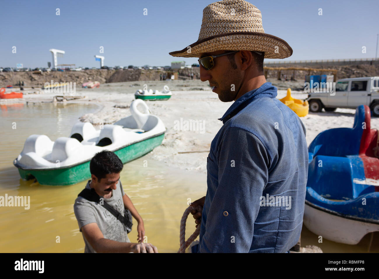 Un giovane uomo in piedi nella spiaggia di sale Urmia Lake e a dare in affitto la barca da diporto, West Azerbaijan provincia, Iran Foto Stock