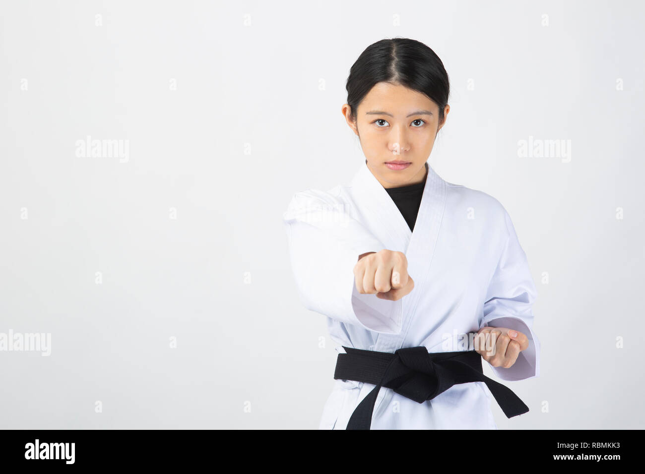 Giovane bella donna che indossa il karate tuta eseguendo il karate su sfondo bianco Foto Stock