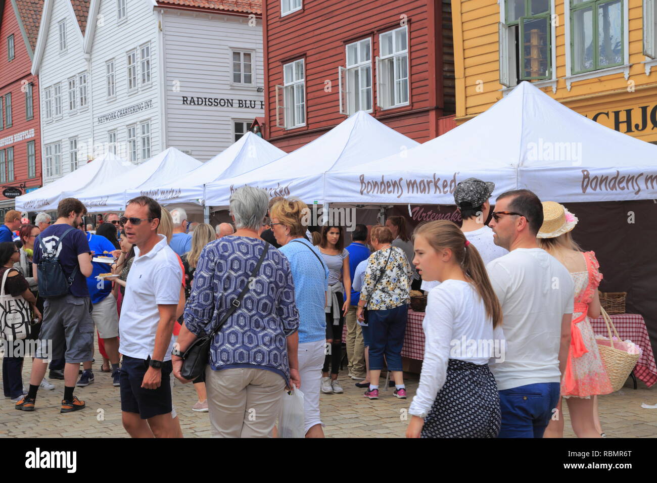 La gente a piedi lungo il Sito Patrimonio Mondiale dell'UNESCO, Bryggen, durante la tradizionale Torgdagen o giorno di mercato a Bergen, Norvegia. Foto Stock