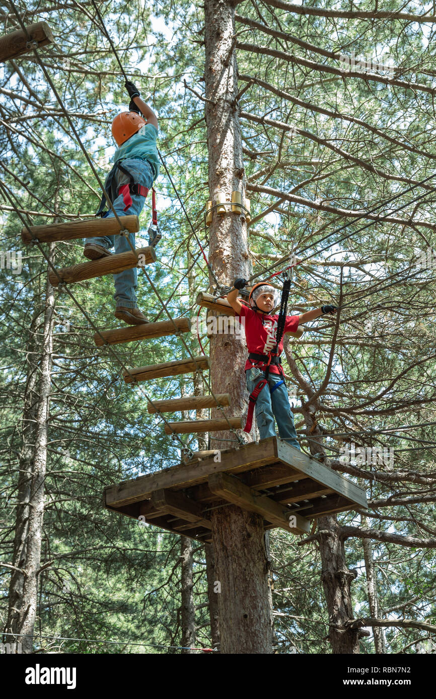 Ragazzo con cablaggio di sicurezza arrampicate nel parco avventura in pineta. Guardiagrele, .Abruzzo, Italia Foto Stock