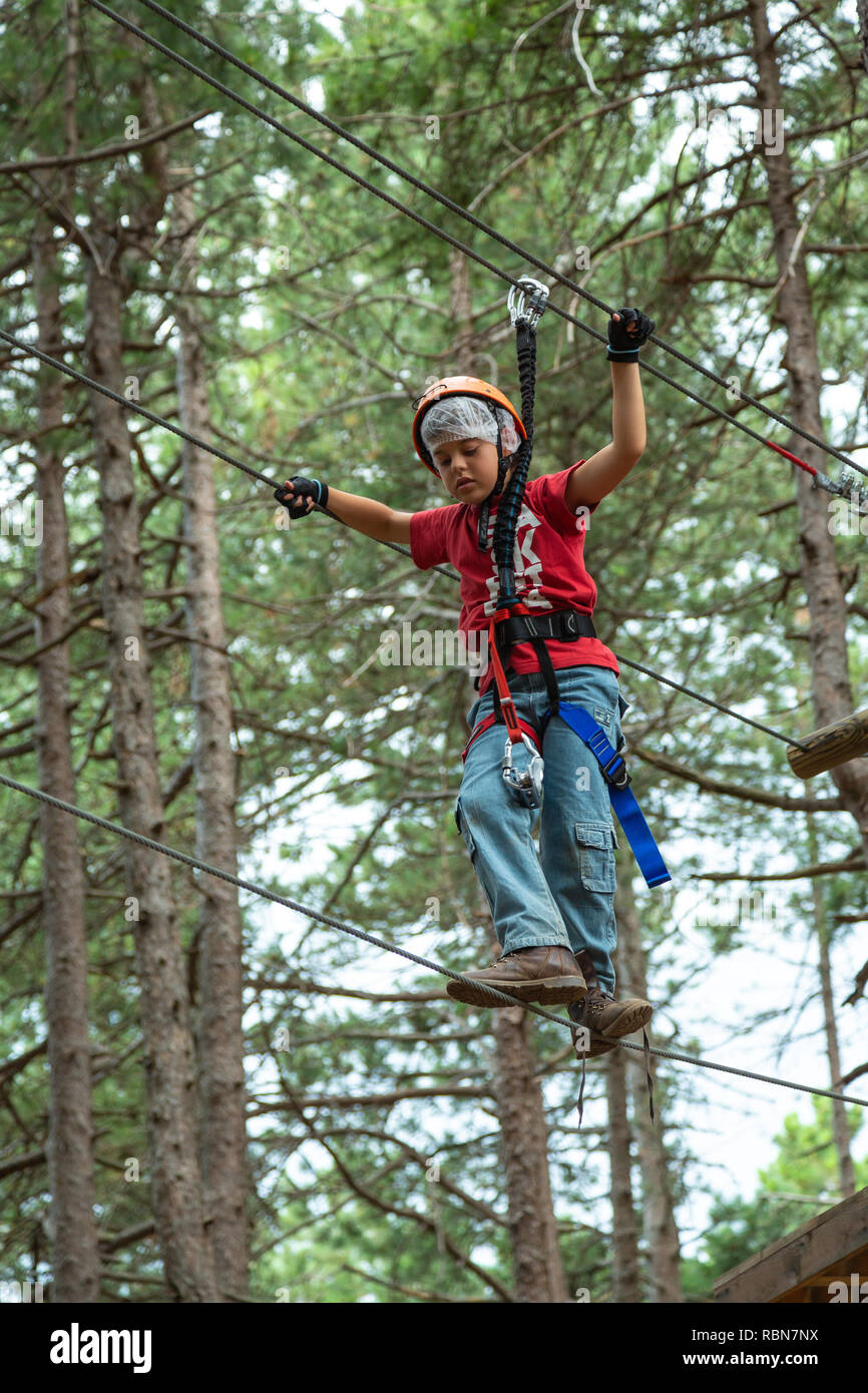 Ragazzo con cablaggio di sicurezza arrampicate nel parco avventura in pineta. Guardiagrele, .Abruzzo, Italia Foto Stock