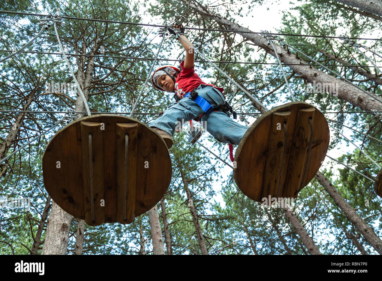 Ragazzo con cablaggio di sicurezza arrampicate nel parco avventura in pineta. Guardiagrele, .Abruzzo, Italia Foto Stock