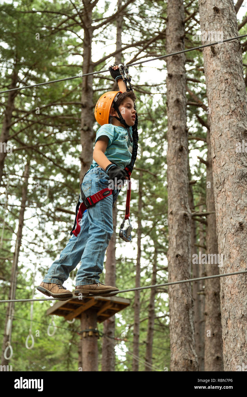 Ragazzo con cablaggio di sicurezza arrampicate nel parco avventura in pineta. Guardiagrele, .Abruzzo, Italia Foto Stock