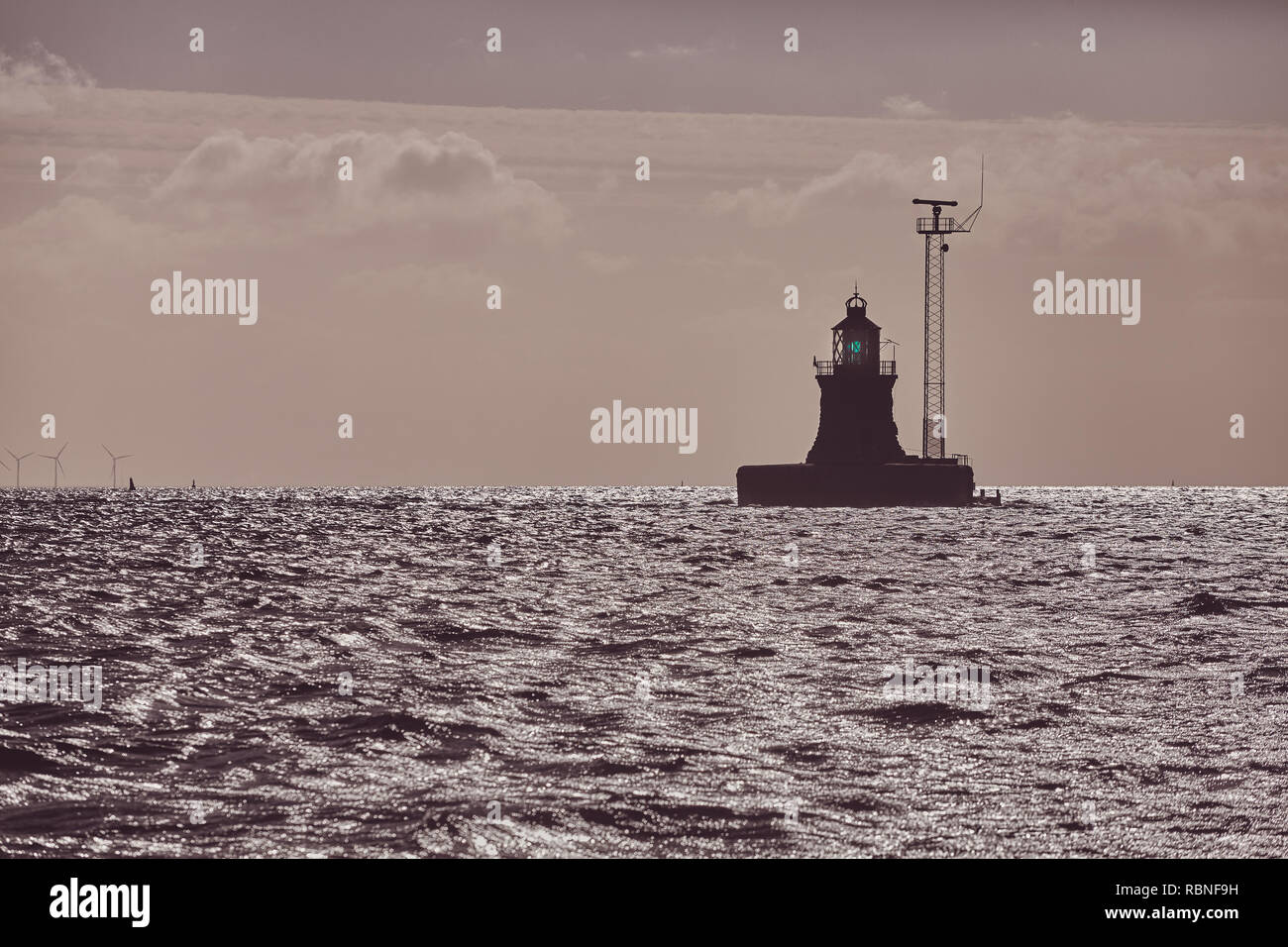 Silhouette di un faro all'orizzonte al tramonto, il fuoco selettivo, tonificazione del colore applicato. Foto Stock