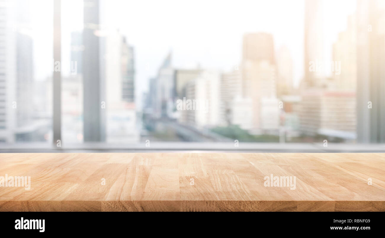Svuotare tavolo in legno con blur ufficio in camera e nella finestra vista città sfondo.per montaggio display del prodotto o chiave di progettazione layout visivo. Foto Stock