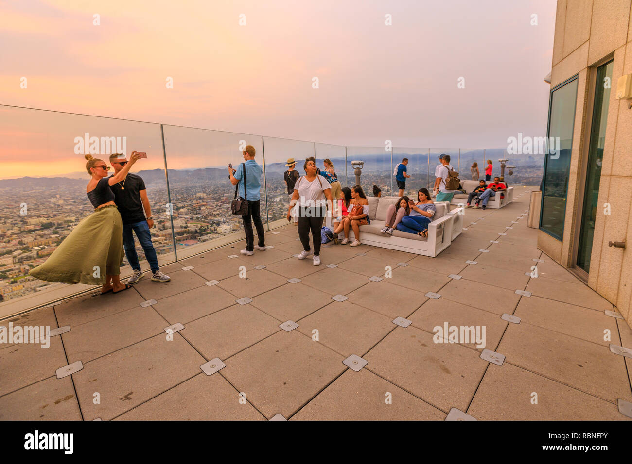 Los Angeles, California, Stati Uniti - 9 Agosto 2018: giovane tenendo selfie aperto sulla terrazza panoramica al tramonto. Per coloro che godono di vedute della La della skyline del centro da Oue Skyspace U.S. Torre della banca. Foto Stock