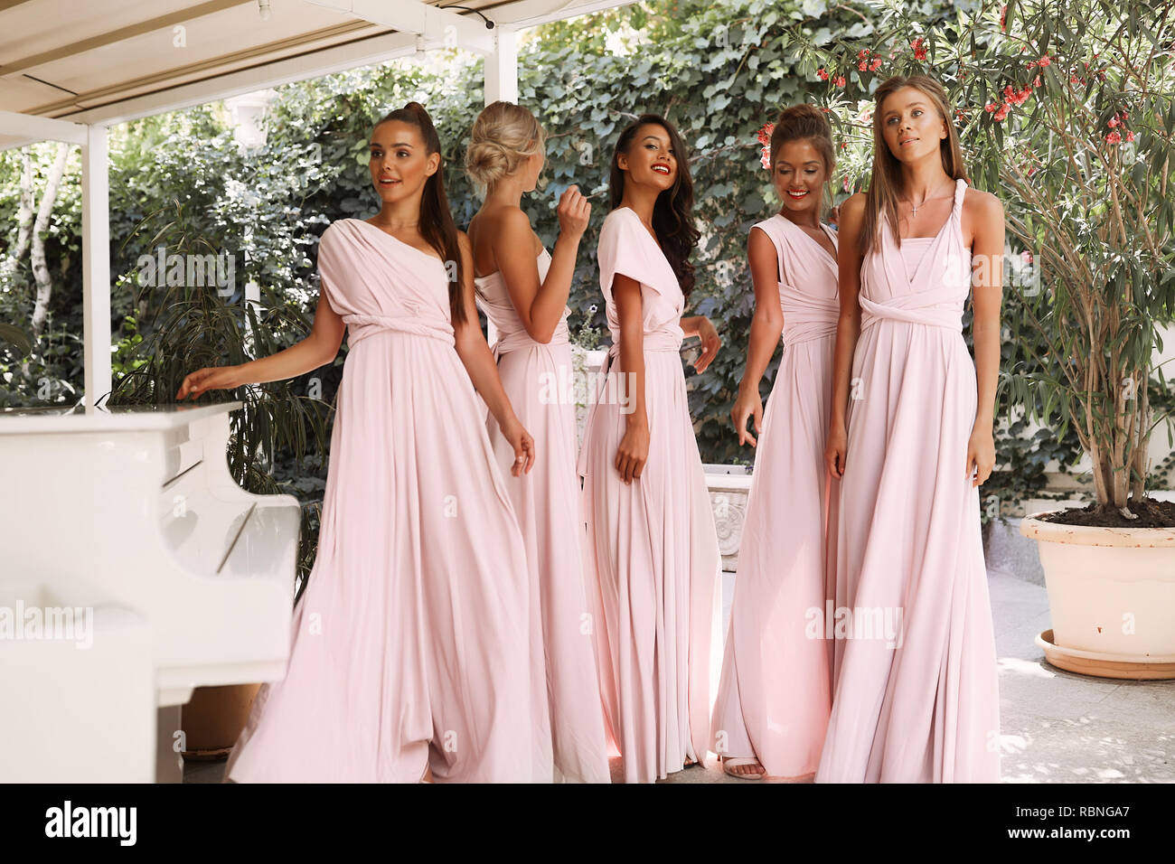 Silph ragazze nella luce rosa vestiti in piedi vicino al pianoforte, terrazza, ristorante , event, party, trucco, capelli stile, moda, bellezza, divertendosi Foto Stock