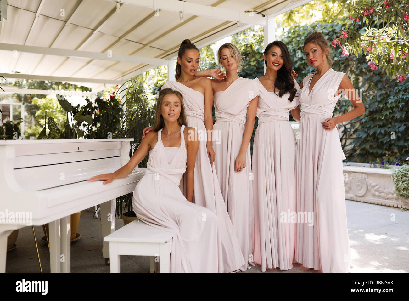 Gara femminile ladies della luce rosa vestiti in piedi vicino al pianoforte, terrazza, ristorante , event, party, trucco, capelli stile, moda, bellezza Foto Stock