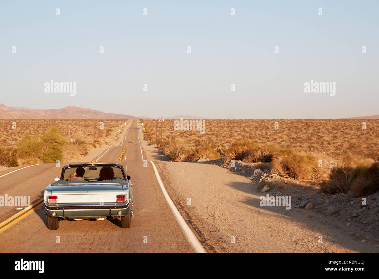 Giovane guida auto convertibili su deserto autostrada, Vista posteriore Foto Stock