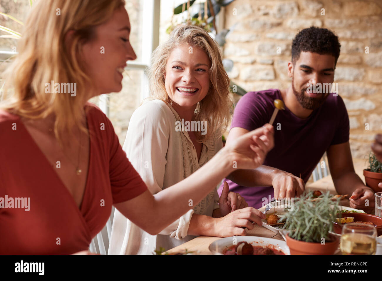 Tre giovani amici divertendosi mangiare tapas in un ristorante Foto Stock