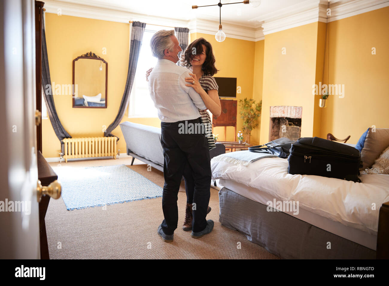 Coppia di mezza età abbracciare, Sorridenti nella loro camera di albergo Foto Stock