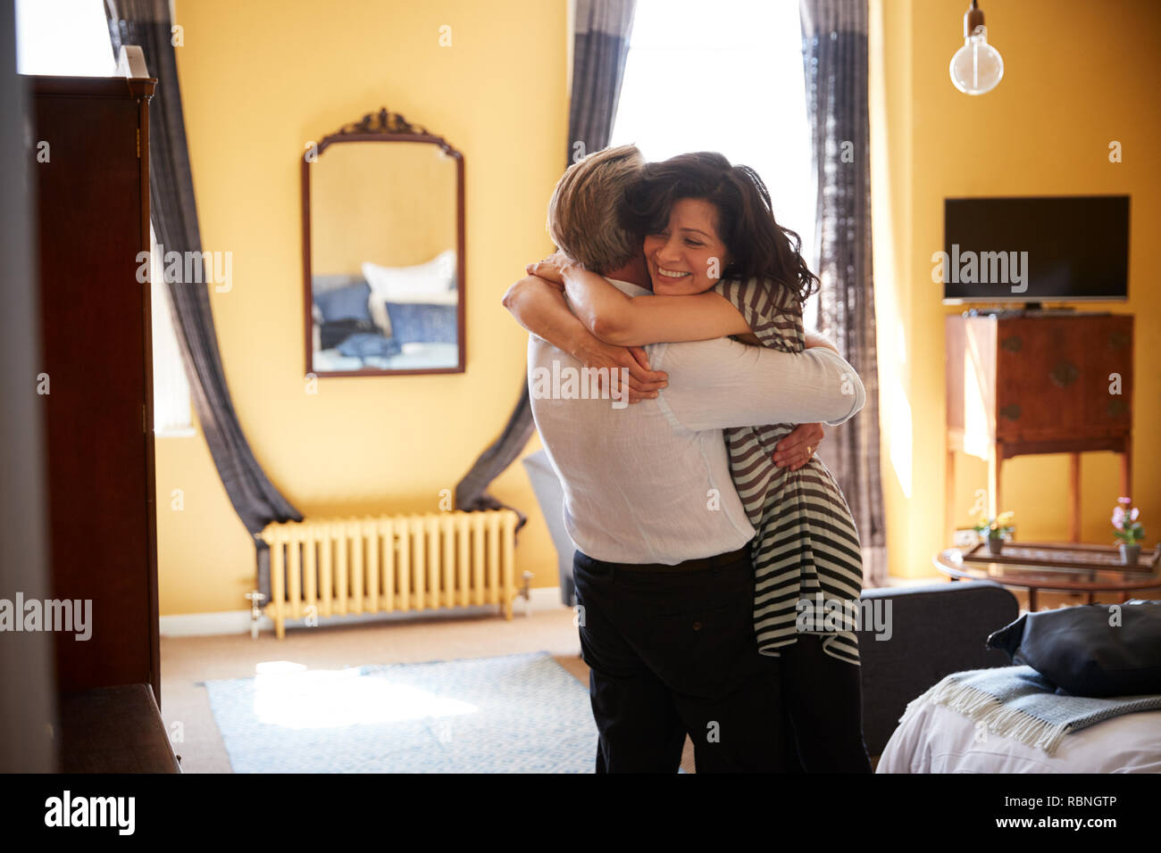 Coppia di mezza età abbracciando nella loro camera d'albergo, vicino fino Foto Stock