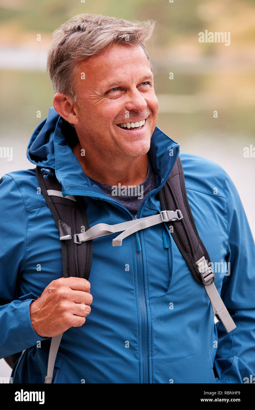 Uomo adulto su una vacanza in campeggio che guarda lontano sorridente, vicino Lake District, REGNO UNITO Foto Stock