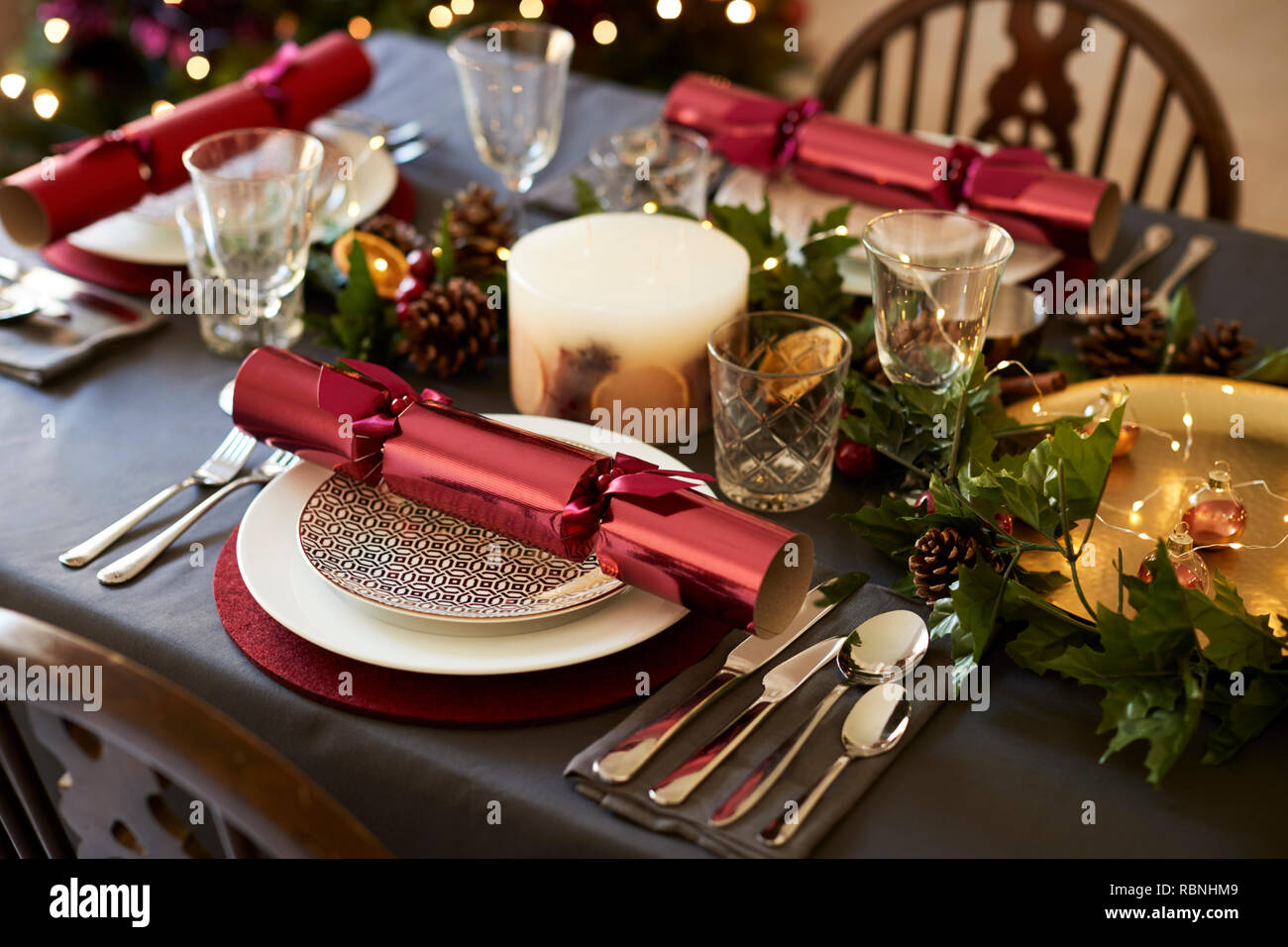 Close up di Natale messa in tavola con cracker di Natale disposti sulle piastre e di colore rosso e verde tabella decorazioni, vista in elevazione Foto Stock