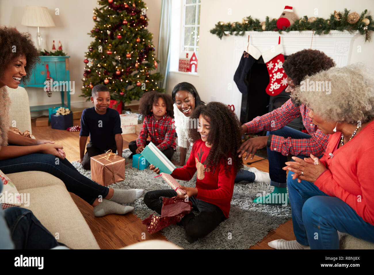 Figlia di apertura come regalo Multi generazione Famiglia festeggiano il Natale a casa insieme Foto Stock