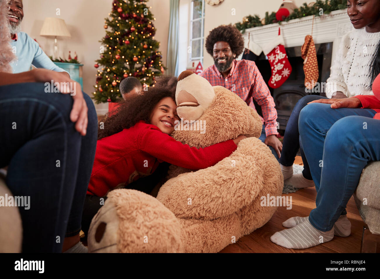 Bambini che giocano con il gigante Orsacchiotto come famiglia Multi-Generation Aprire i Regali il giorno di Natale Foto Stock