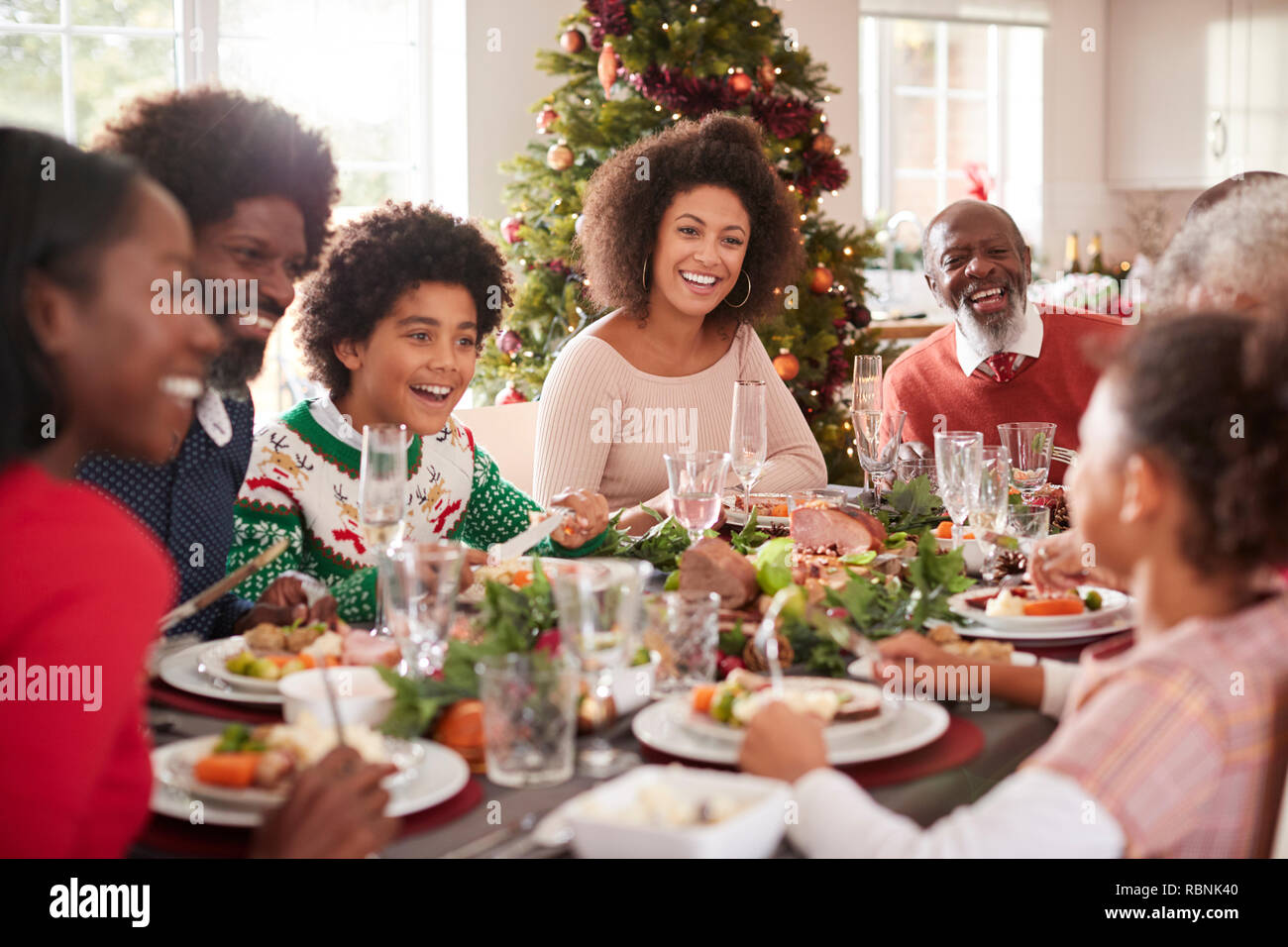 Felice generazione multi razza mista famiglia seduti alla loro cena di Natale tabella mangiare e parlare, il fuoco selettivo Foto Stock