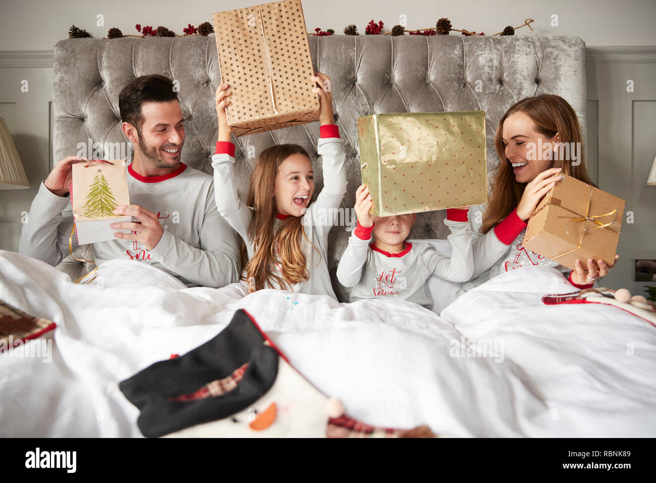 Famiglia eccitato nel letto di casa doni di apertura il giorno di Natale Foto Stock