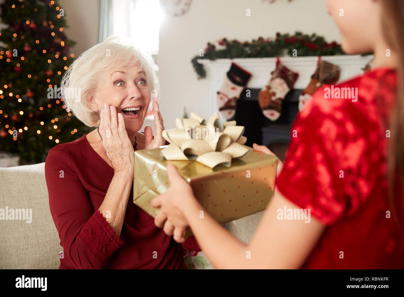 Nonna eccitato ricevere regali di Natale dal nipote a casa Foto Stock
