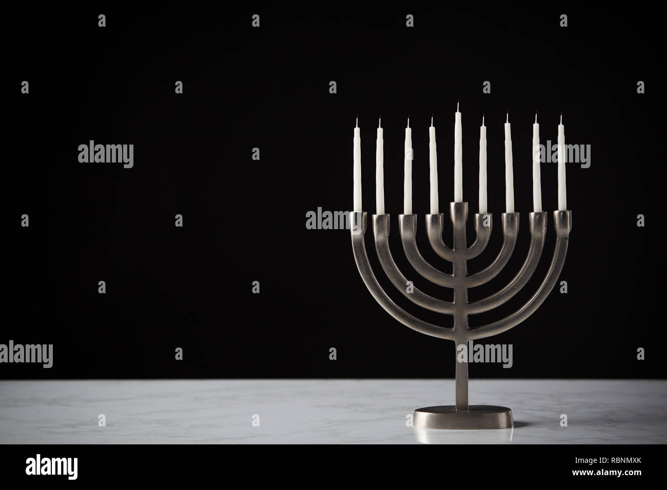 Metallo Hanukkah Menorah con candele non illuminata sulla superficie di marmo contro il nero di sfondo per studio Foto Stock
