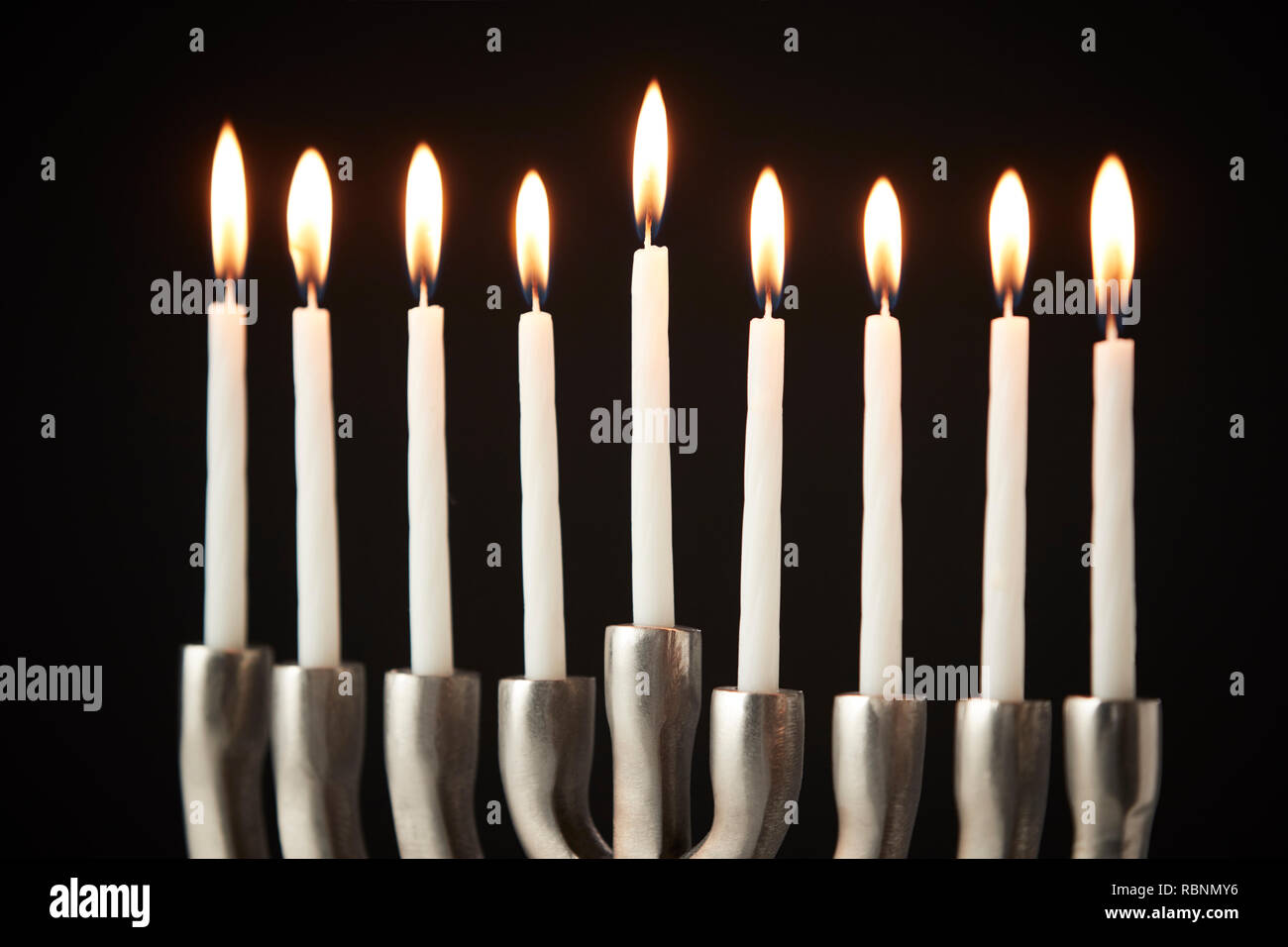 Candele accese sul metallo Hanukkah Menorah contro il nero di sfondo per studio Foto Stock