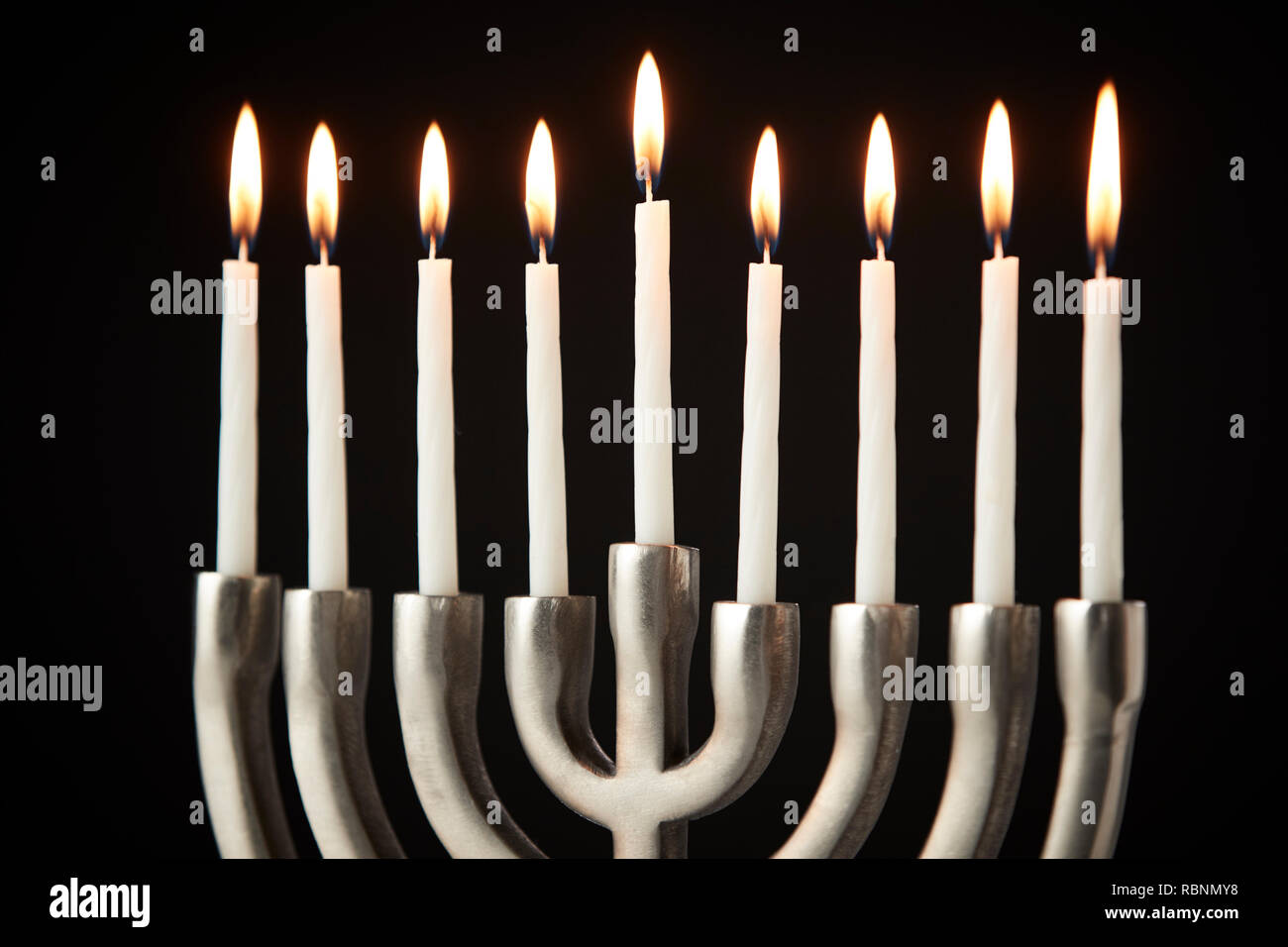 Candele accese sul metallo Hanukkah Menorah contro il nero di sfondo per studio Foto Stock