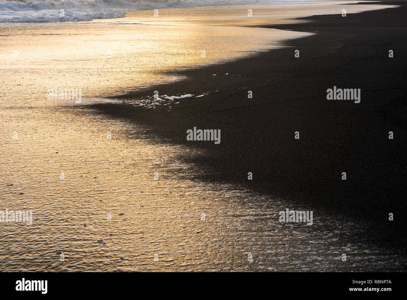 golden surge onde sulla spiaggia nera in Islanda in umore tramonto Foto Stock